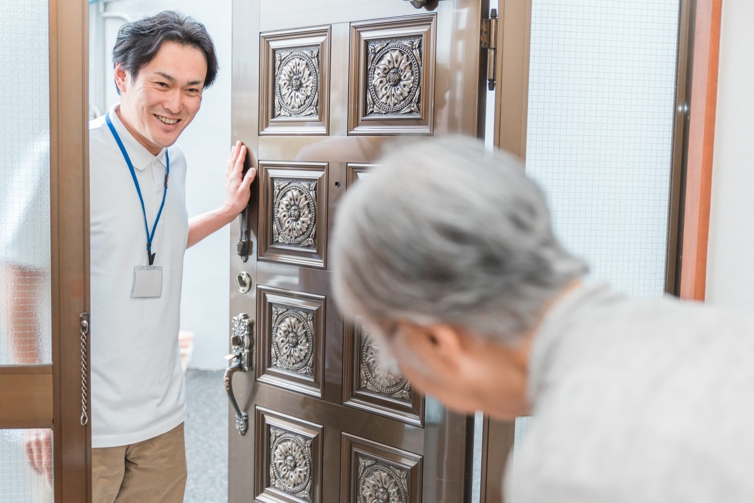 玄関先で高齢の方に声をかける職員のイメージ