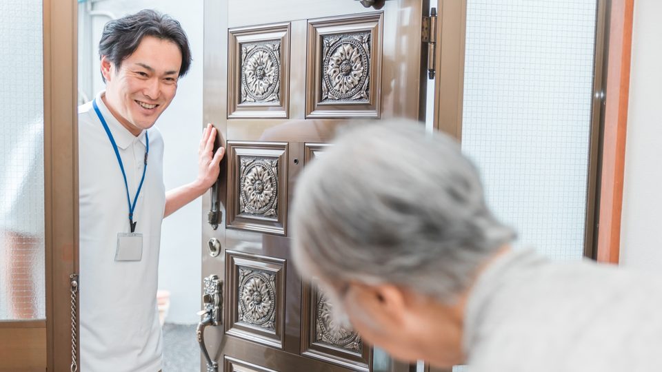 玄関先で高齢の方に声をかける職員のイメージ